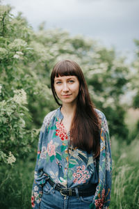 Portrait of smiling young woman standing against plants