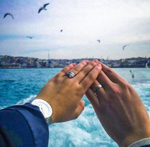 Close-up of hands holding sea against sky