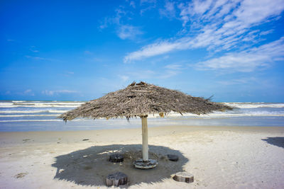 Wooden hut on beach against sky