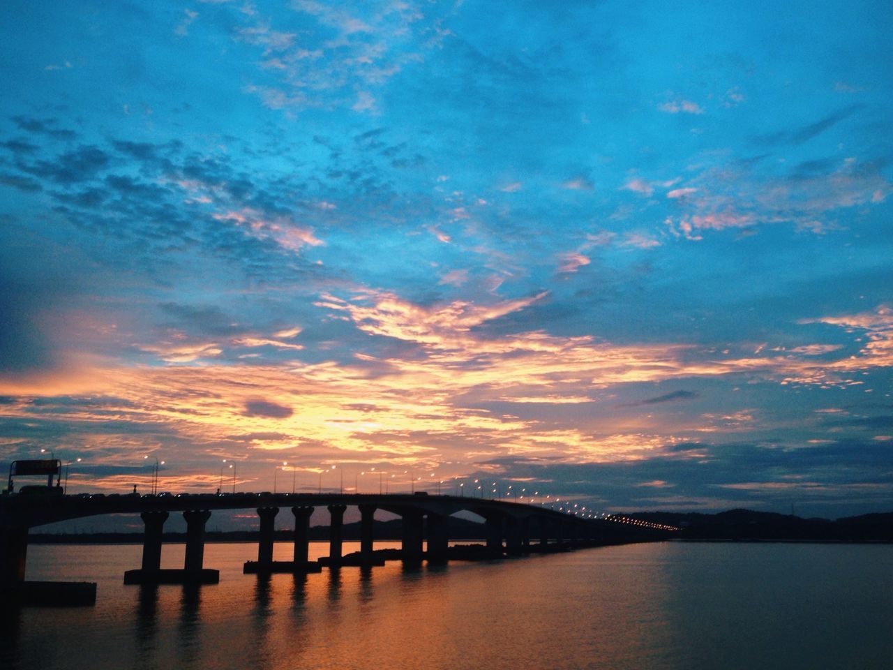 water, sunset, sky, built structure, architecture, waterfront, connection, cloud - sky, bridge - man made structure, tranquility, tranquil scene, reflection, scenics, beauty in nature, pier, river, silhouette, nature, bridge, cloud