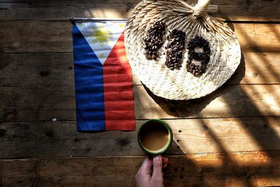 Cropped hand holding coffee in front of philippines flag and number on table