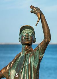 Statue by sea against sky