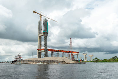 Crane by sea against sky