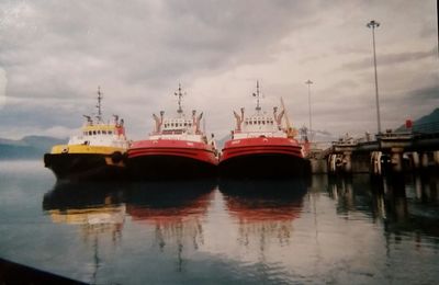 Boats in calm sea against cloudy sky