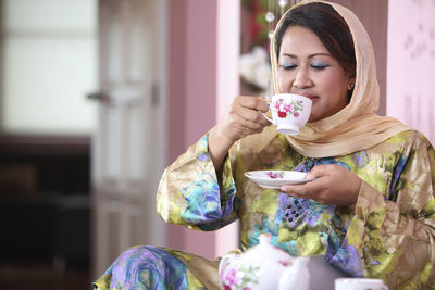 Woman drinking coffee while sitting at home