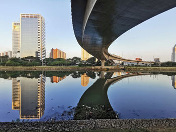 Arch bridge over river by buildings against sky