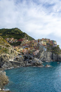 Buildings by sea against sky