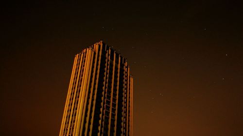 High section of illuminated building against sky at night