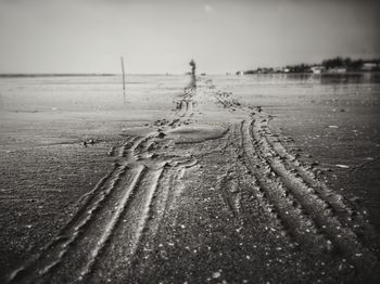 Close-up of wet sand on beach against sky