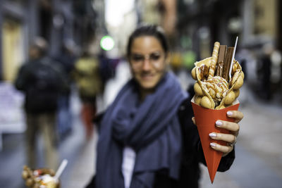 Woman holding ice cream standing outdoors