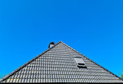 Open roof window in velux style with black roof tiles