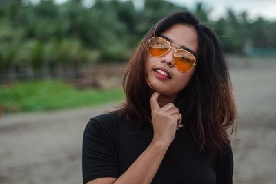 Portrait of young woman wearing sunglasses standing outdoors