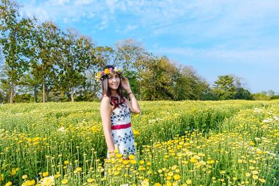 Portrait of woman wearing flowers while standing in farm