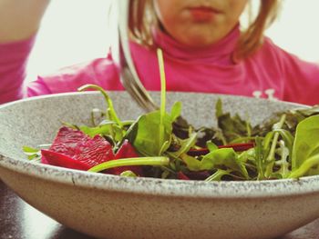 Close-up of salad in bowl with girl in background