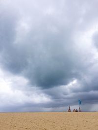 People on beach against cloudy sky