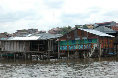 Houses by river against sky