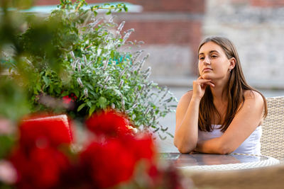 Young woman looking away while sitting outdoors
