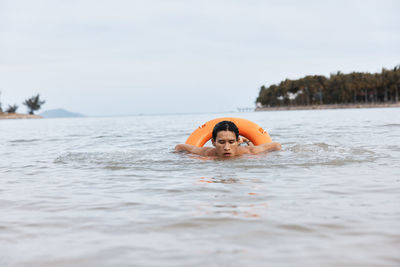 Young woman swimming in sea against sky