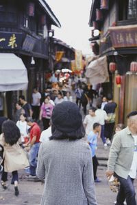 Rear view of people walking on street in city