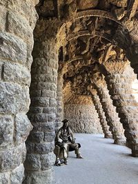 Man leaning on rock against building