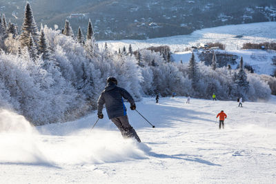 Rear view of man skiing in snow covered forest