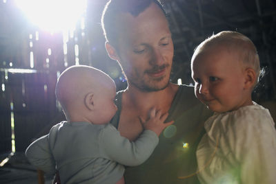 Father carrying babies at backyard during sunny day