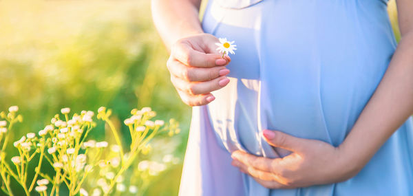 Midsection of pregnant woman showing flower