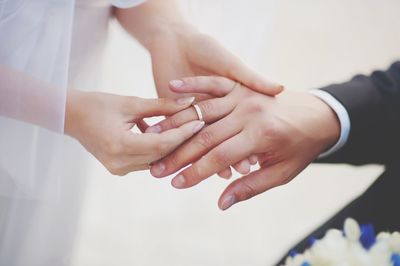 Midsection of couple exchanging wedding ring