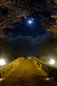 Illuminated street light against sky at night