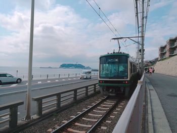 Train on railroad tracks in city against sky