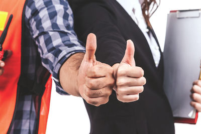 Midsection of engineer with colleague showing thumbs up signs