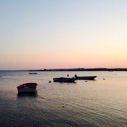 Boats in sea at sunset