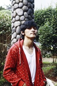 Portrait of young man standing against trees