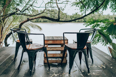 Empty chairs and table by lake