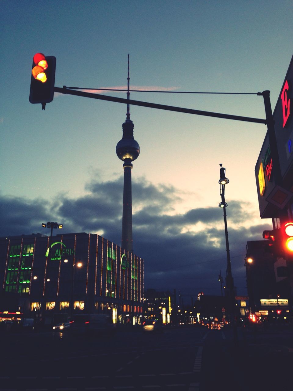 building exterior, communication, sky, street light, city, architecture, illuminated, built structure, communications tower, street, low angle view, dusk, transportation, tall - high, tower, travel destinations, road sign, cloud - sky, lighting equipment, fernsehturm