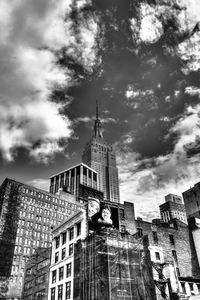 Low angle view of city buildings against cloudy sky