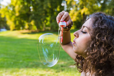 Close-up of young woman with bubbles in park