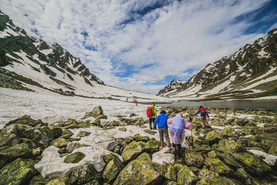 Rear view of people walking on mountain against sky