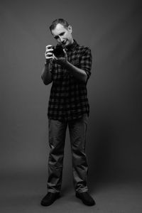 Full length portrait of young man standing against gray background