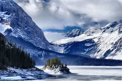 Snowcapped mountain range against cloudy sky