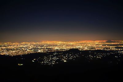 Illuminated cityscape against sky at night