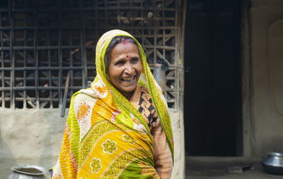 Portrait of a smiling woman wearing sari outside her house in rural village in india 
