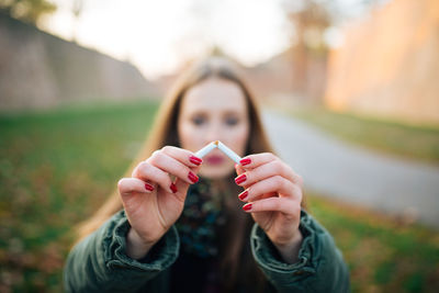 Young woman breaking cigarette on field