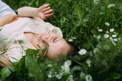 Beautiful woman with natural beauty without makeup lies in the grass in summer
