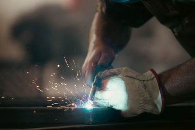 Cropped hands of welder working at factory