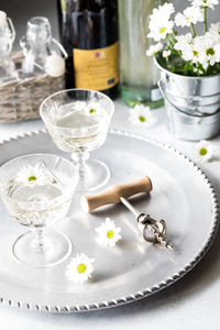 Glasses of white wine on a silver tray garnished with white flowers.