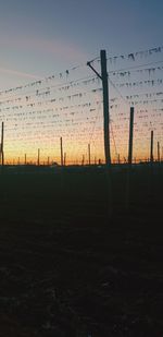 Silhouette fence on field against sky during sunset