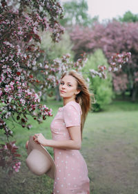 Beautiful young pretty woman in a light dress walks in a blooming spring park