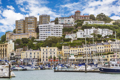 Boats moored at harbor against buildings in city