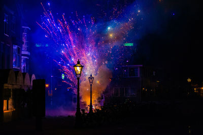 Firework display in city against sky at night